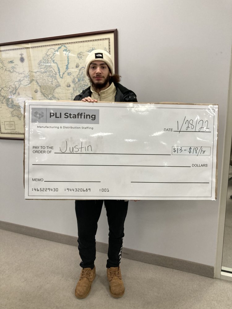 Justin holding his PLI Staffing placement check in the Middleburg Heights office, dated 28 January 2022.