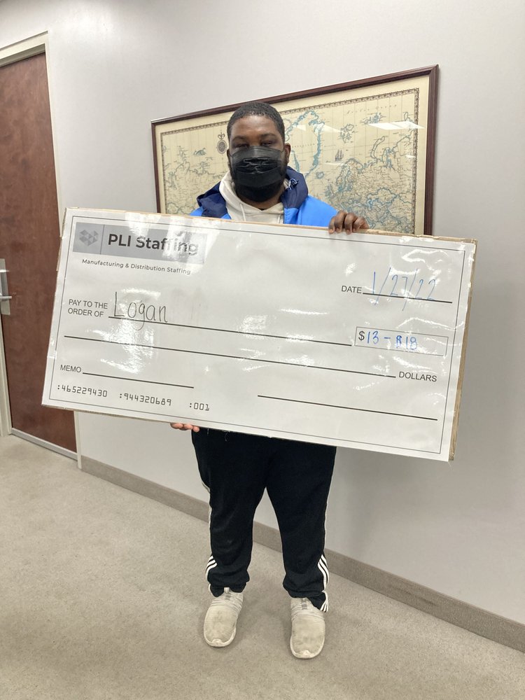 Logan holding his PLI Staffing placement check in the Middleburg Heights office, dated 27 January 2022.