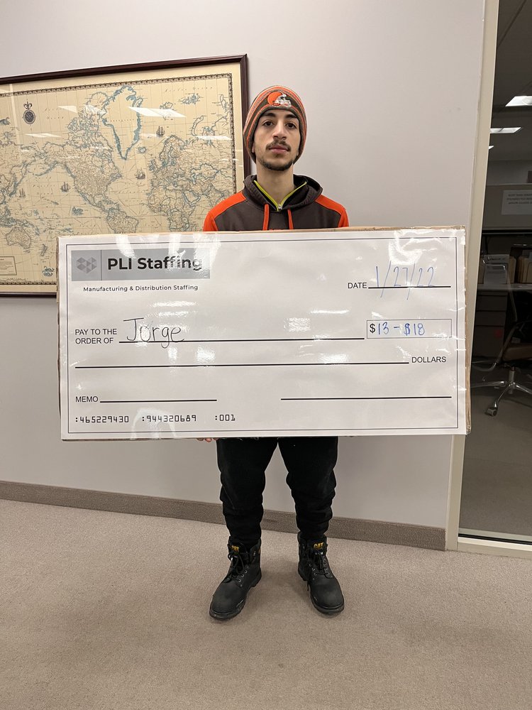 Jorge holding his PLI Staffing placement check in the Middleburg Heights office, dated 27 January 2022.